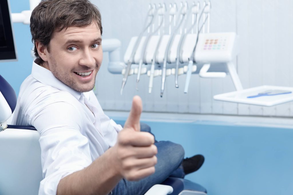 A happy male patient showing the thumbs up at the dentist
